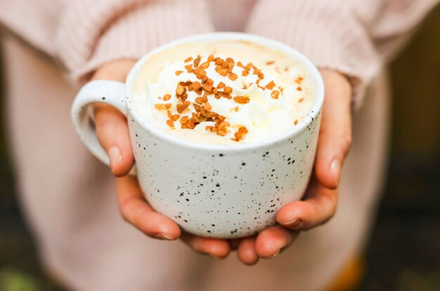 Granos de azúcar moreno en espuma de café en una taza de cerámica blanca