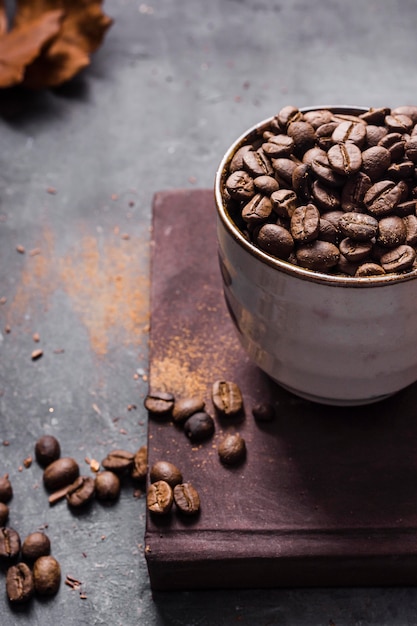 Granos de café de ángulo alto en taza sobre tabla de cortar