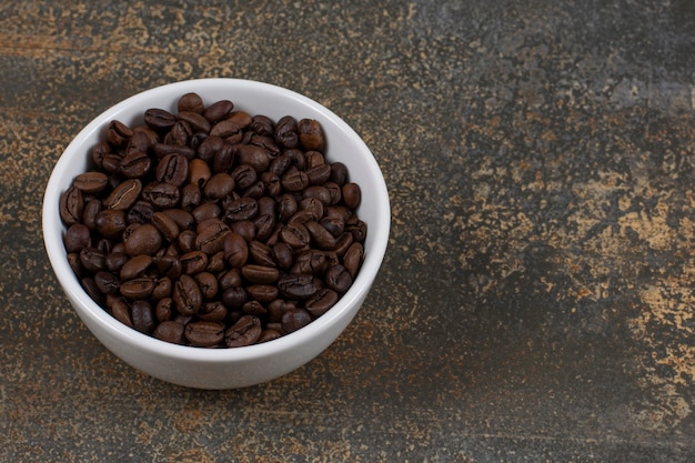 Granos de café aromáticos en un tazón blanco.