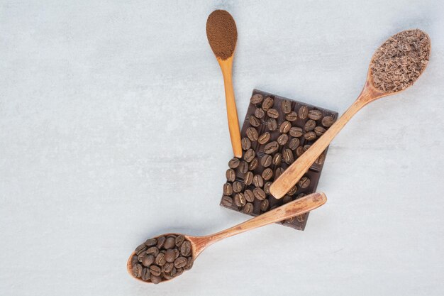 Granos de café, café molido y cacao en polvo en cucharas de madera. Foto de alta calidad