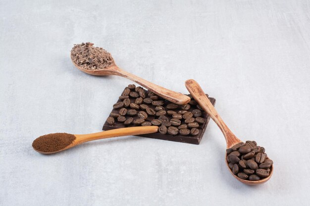Granos de café, café molido y cacao en polvo en cucharas de madera