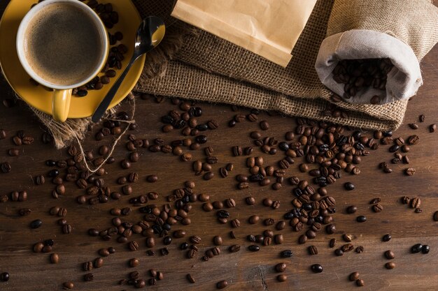 Granos de café colocados en el escritorio con saco y taza