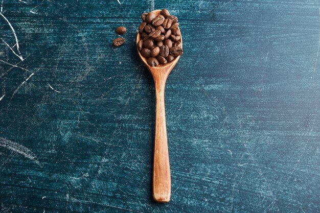 Granos de café en una cuchara de madera.