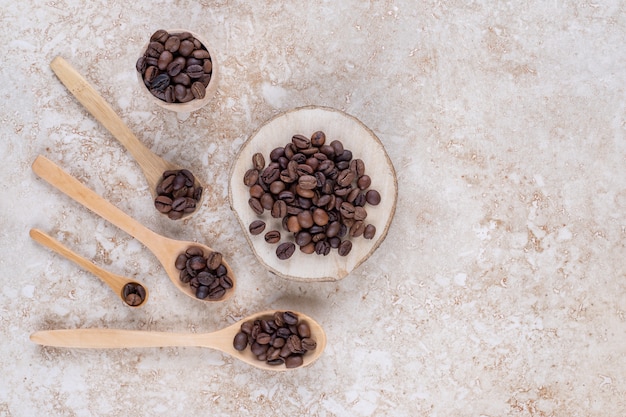 Granos de café en cucharas, un trozo de madera y una taza pequeña.