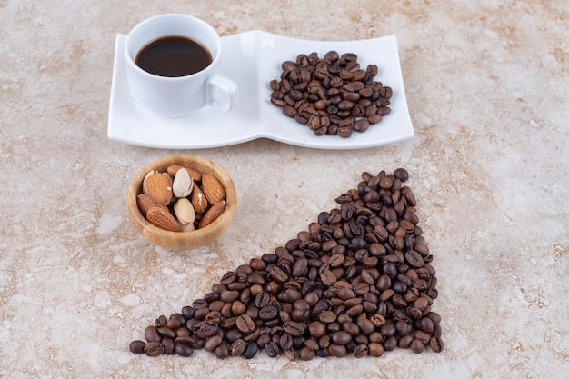 Granos de café, frutos secos variados y una taza de café.