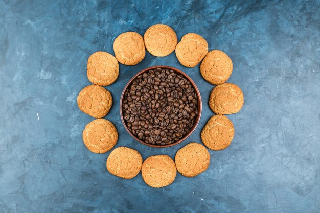 Granos de café con galletas sobre fondo azul oscuro