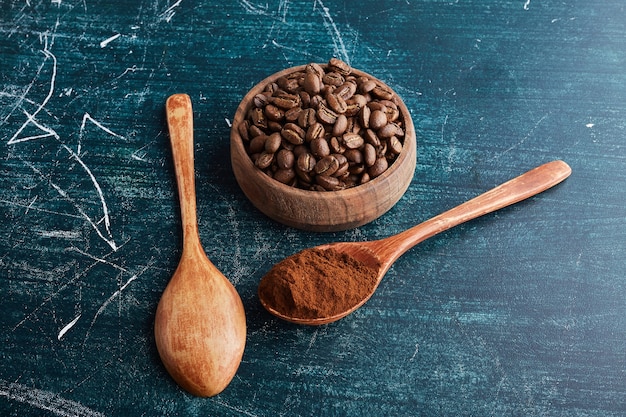 Granos de café marrón en taza y cucharas de madera.