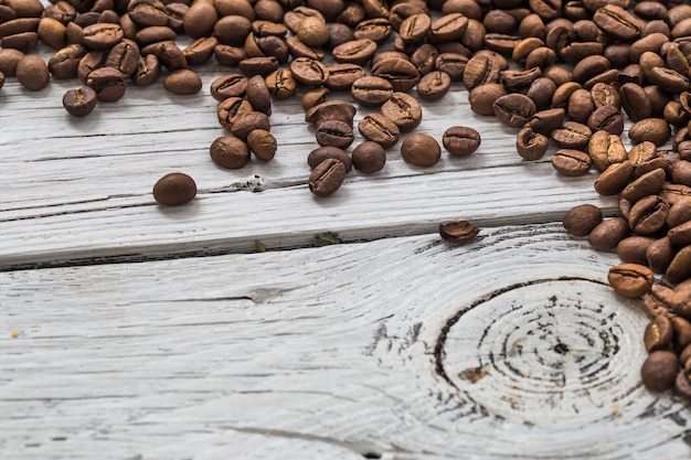 Granos de café en la pared de madera blanca, primer plano