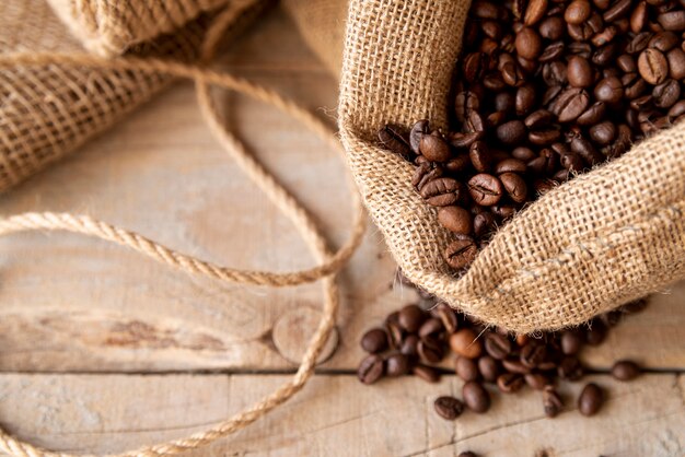 Granos de café en saco de arpillera sobre madera contrachapada