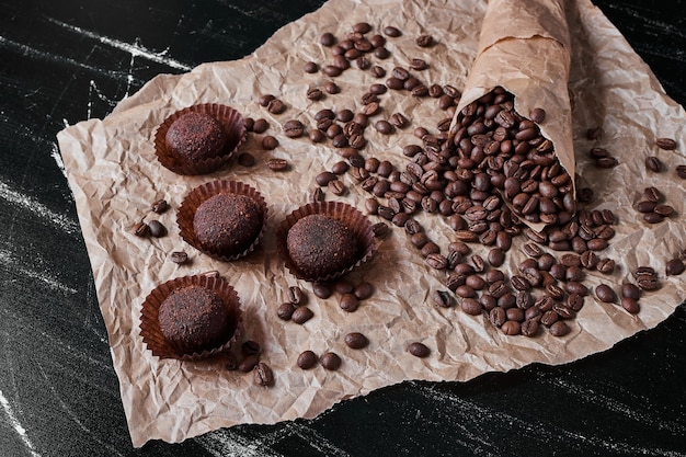 Foto gratuita granos de café sobre fondo negro con pralinés.