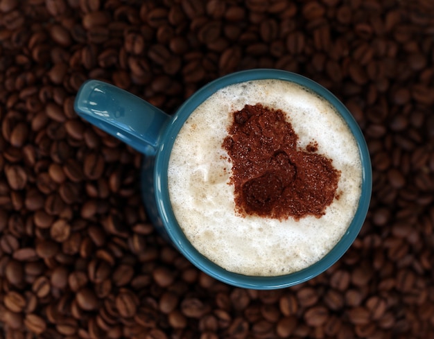 Foto gratuita granos de café con taza en el medio