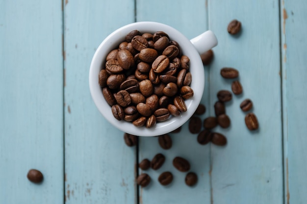 Foto gratuita granos de café en taza sobre fondo azul de madera vieja