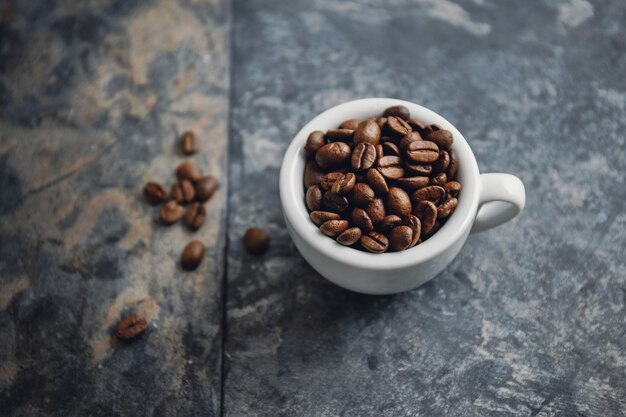 Granos de café en taza sobre fondo de piedra