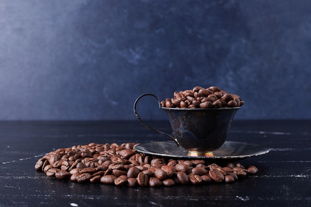 Granos de café en una taza y sobre el negro