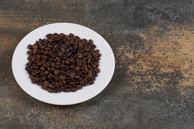 Granos de café tostados en un plato blanco.