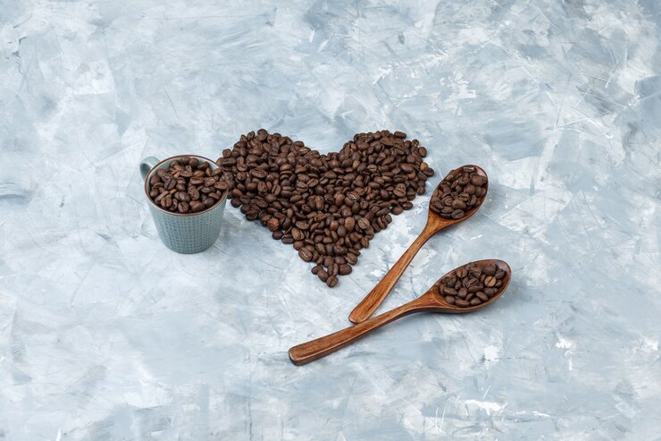 Foto gratuito granos de café de vista de ángulo alto en taza y cucharas de madera sobre fondo de yeso gris. horizontal