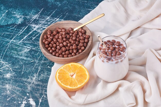 Granos de chocolate con una taza de bebida en azul.