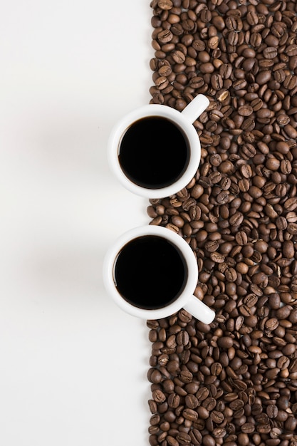 Foto gratuita granos tostados de café y tazas de café blanco.