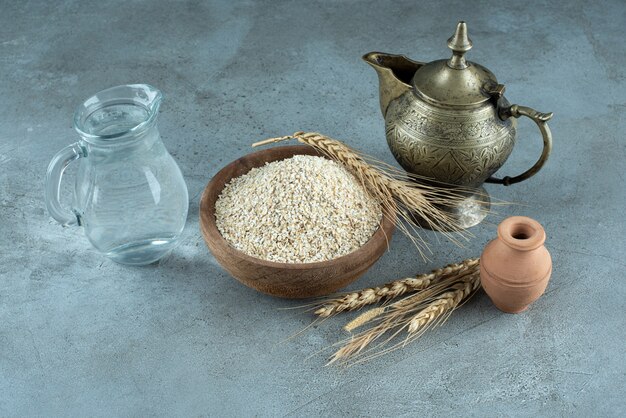 Granos de trigo o arroz en una taza de madera sobre fondo azul. Foto de alta calidad