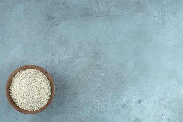 Granos de trigo o arroz en una taza de madera sobre fondo azul. Foto de alta calidad