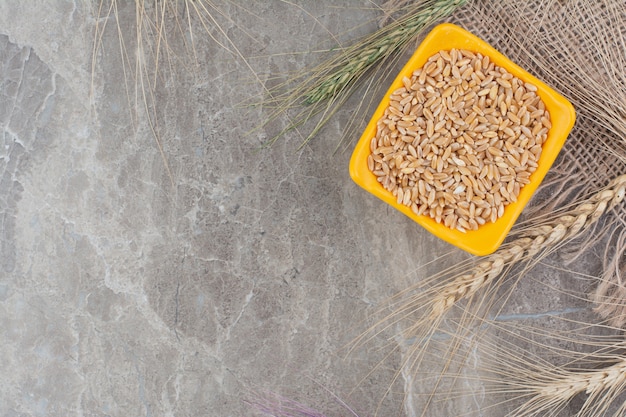 Foto gratuita granos de trigo en taza de cerámica de color naranja.