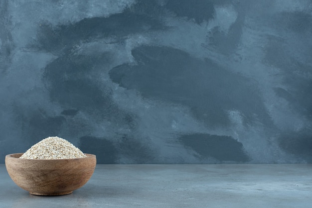 Granos de trigo en una taza de madera sobre fondo azul. Foto de alta calidad