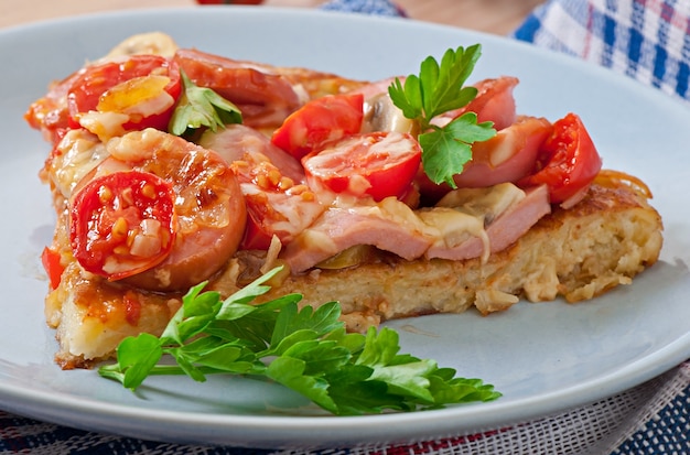 Gratinado de papas - pizza con salchichas, champiñones y tomates