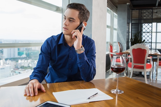 Grave hombre de negocios joven que habla en smartphone