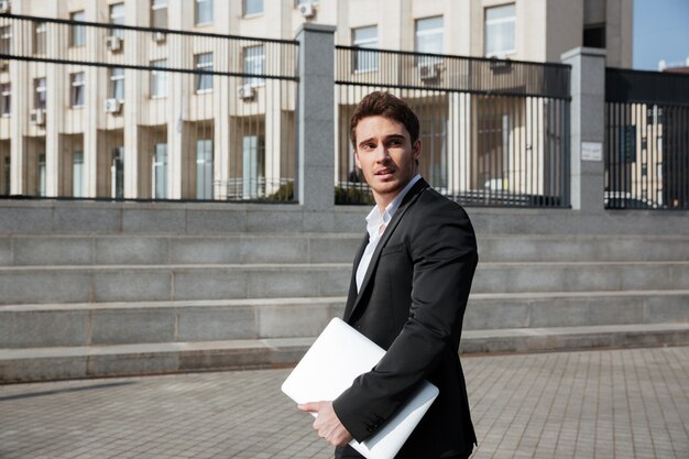 Grave joven empresario caminando al aire libre