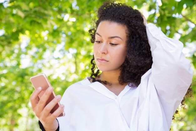 Grave joven y guapa con smartphone en el parque