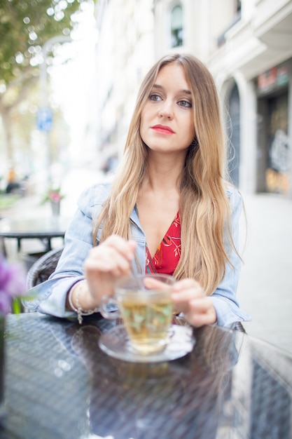 Grave joven mujer hermosa en el café de verano