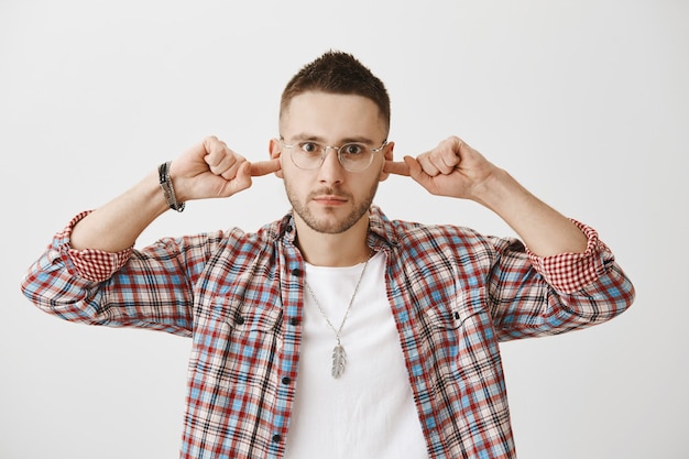 Foto gratuita grave joven preocupado con gafas posando