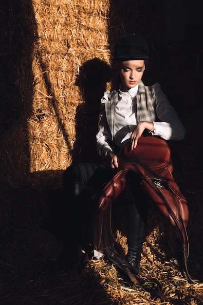 Grave joven sentada en el granero con seddle