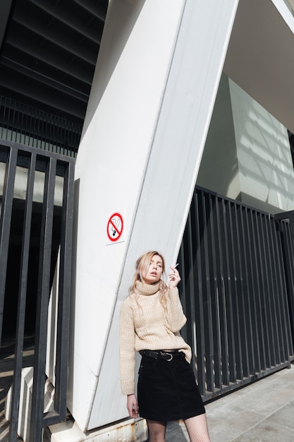 Foto gratuita grave jovencita rubia con cigarrillo