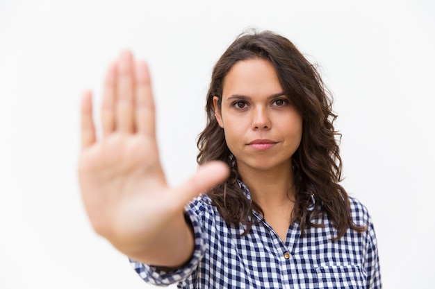 Foto gratuita grave mujer latina decidida haciendo gesto de parada de mano