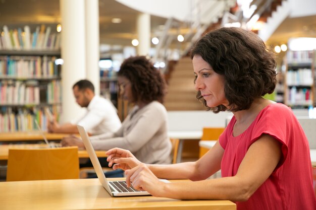 Grave mujer de mediana edad centrada trabajando en investigación