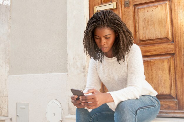 Grave mujer negra navegando por internet móvil en el teléfono