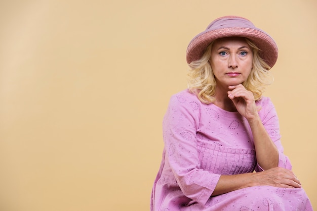 Foto gratuita grave mujer senior con un sombrero rosa