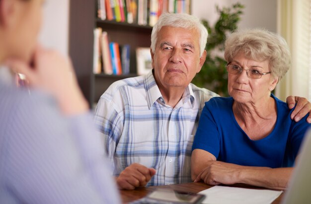 Grave pareja senior sentada en la oficina