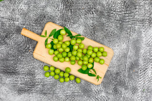 Greengages con hojas en una tabla de cortar en gris sucio. vista superior.