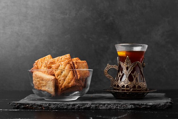 Grietas crujientes en una taza de vidrio con un vaso de té en una tabla de piedra.