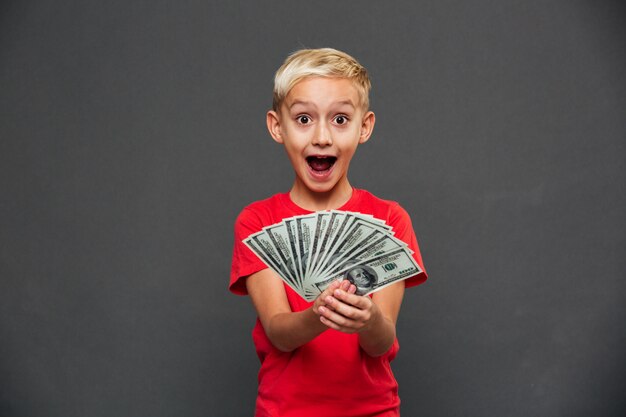 Gritando sorprendido niño niño mostrando dinero.