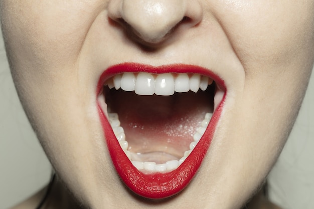 Gritos enojados. Sesión de primer plano de boca femenina con maquillaje de labios rojo brillante y piel de mejillas bien cuidada.