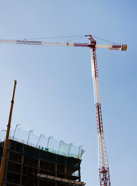 Grúa de construcción roja y blanca delante del edificio contra el cielo azul