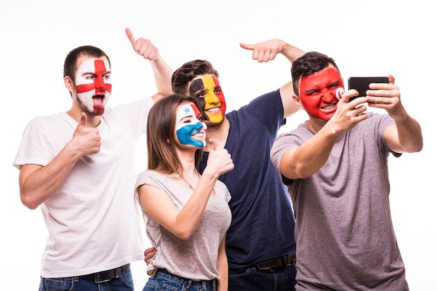 Grupo de aficionados apoyan a sus selecciones nacionales con caras pintadas. Inglaterra, Bélgica, Túnez, Panamá Fans toman selfie en teléfono aislado sobre fondo blanco.