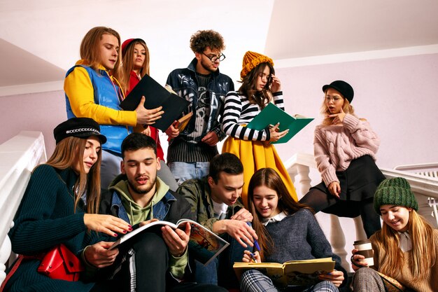 El grupo de alegres estudiantes felices sentados en una sala de conferencias antes de la lección