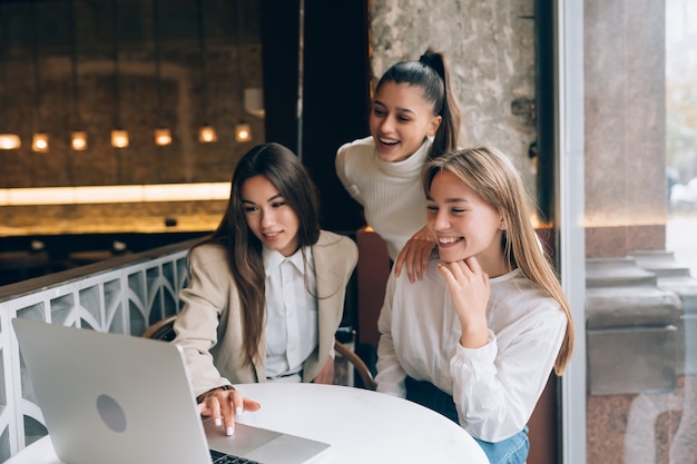 Un grupo de amigas en un café está mirando una computadora portátil