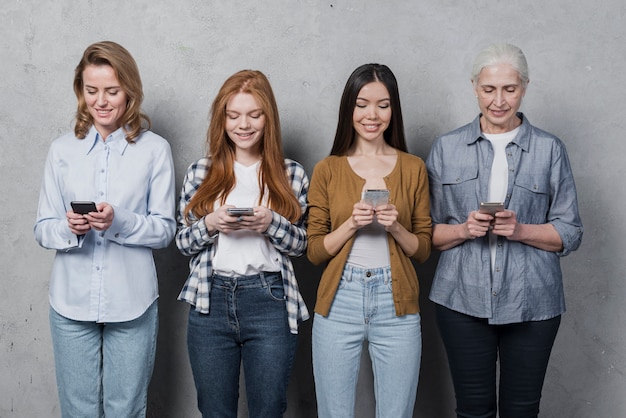 Grupo de amigas enviando mensajes de texto por teléfono