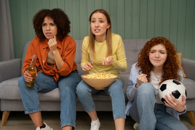 Foto gratuita grupo de amigas y fans de los deportes viendo la televisión en casa juntos