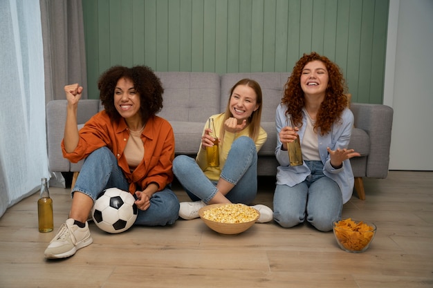 Foto gratuita grupo de amigas y fans de los deportes viendo la televisión en casa juntos